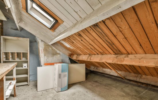 an unfinished attic with wood paneling on the walls and ceiling that has been stripped off to make room for new appliances
