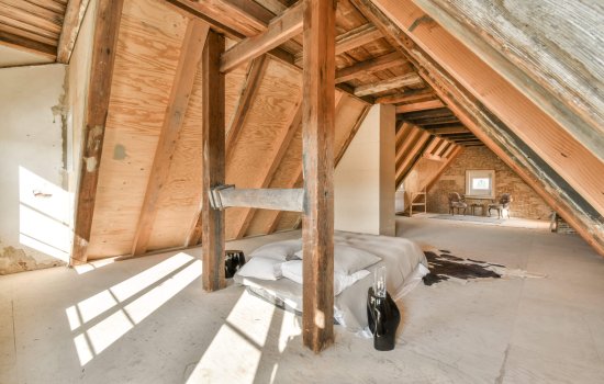 Comfortable bed placed near green wall in modern minimalist style mansard bedroom with windows